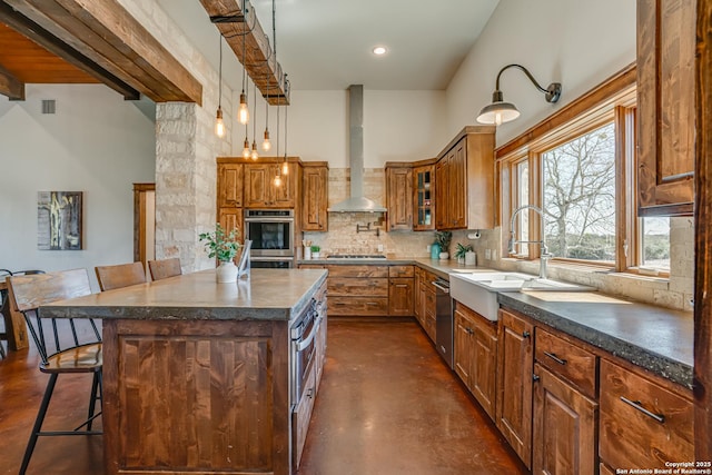 kitchen featuring a breakfast bar, stainless steel appliances, backsplash, a sink, and wall chimney range hood