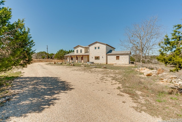 view of front of property featuring metal roof, stone siding, and a standing seam roof