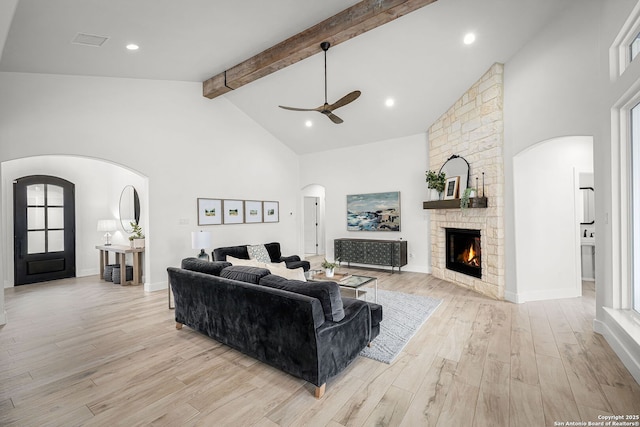 living room with arched walkways, high vaulted ceiling, beam ceiling, and light wood-style floors