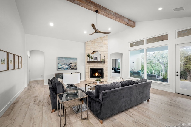 living area featuring arched walkways, high vaulted ceiling, a fireplace, beam ceiling, and light wood finished floors