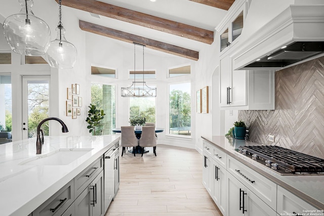 kitchen with beam ceiling, stainless steel gas cooktop, custom exhaust hood, tasteful backsplash, and a sink