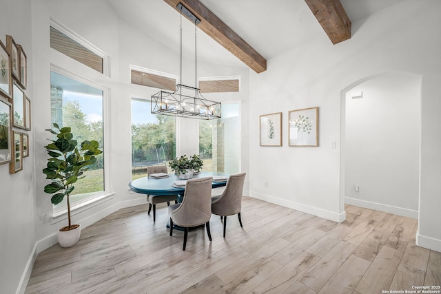 dining room with light wood-type flooring, plenty of natural light, beamed ceiling, and an inviting chandelier