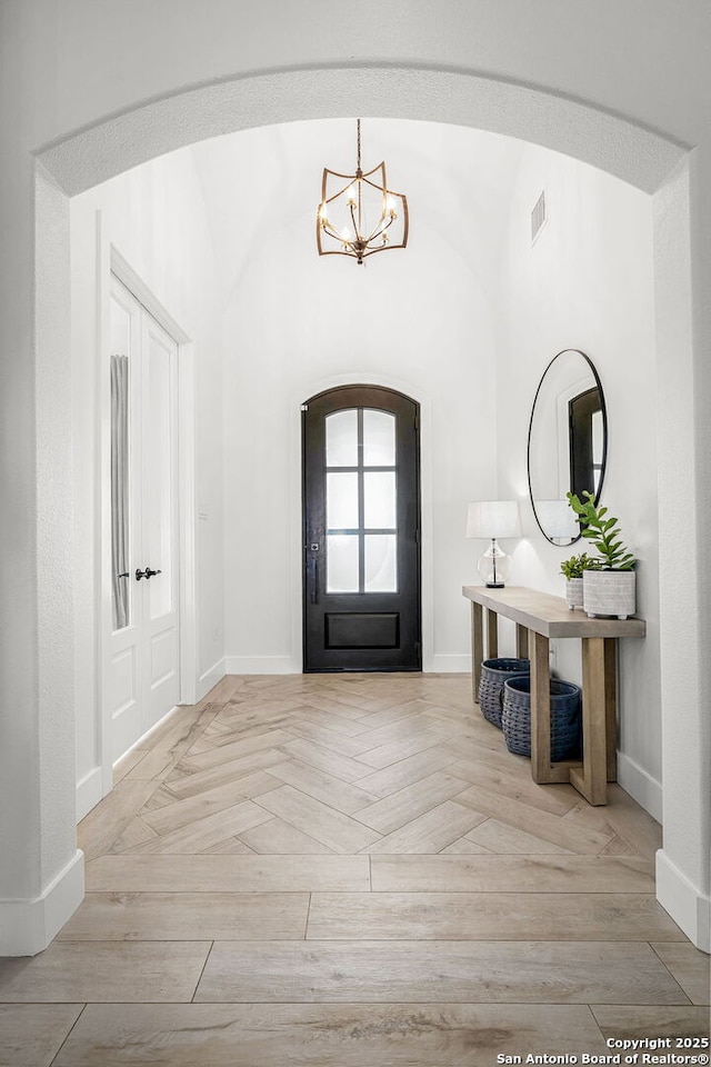 foyer featuring arched walkways, visible vents, and baseboards