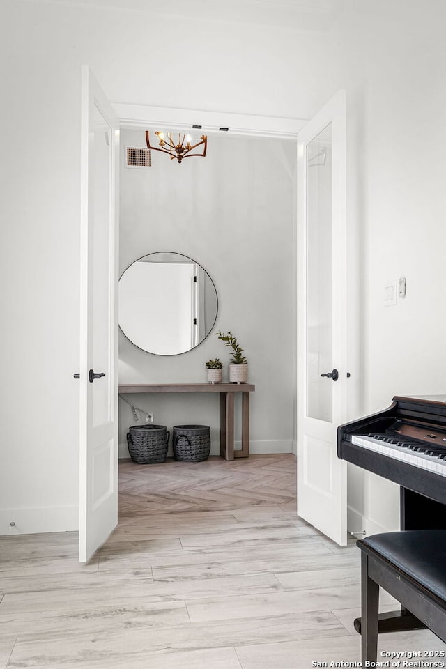 interior space featuring baseboards, visible vents, a chandelier, and wood finished floors