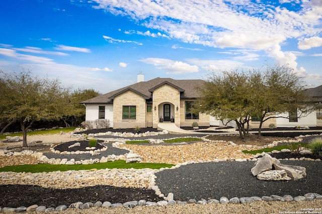 french provincial home with stone siding and a chimney