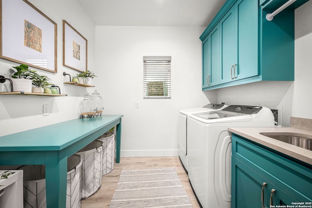 clothes washing area featuring light wood-type flooring, washing machine and dryer, cabinet space, and baseboards