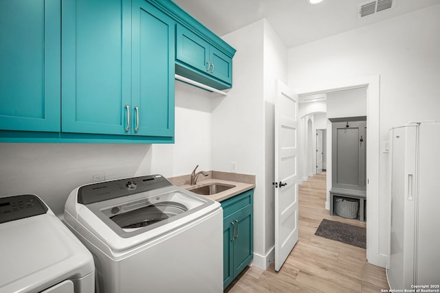 washroom featuring washing machine and clothes dryer, cabinet space, visible vents, light wood-style floors, and a sink