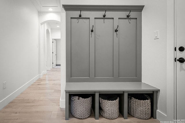 mudroom featuring arched walkways, light wood-type flooring, and baseboards