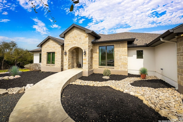 view of front of home featuring stone siding and roof with shingles