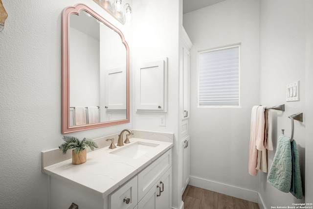 bathroom featuring baseboards, wood finished floors, and vanity