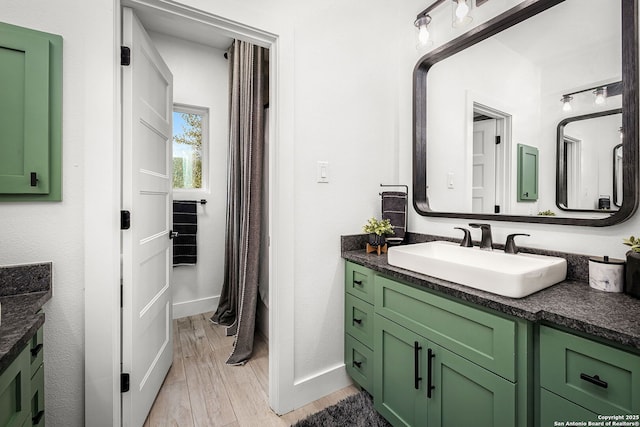 bathroom featuring baseboards, wood finished floors, and vanity