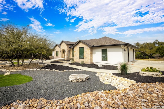 view of front facade with roof with shingles, stucco siding, an attached garage, stone siding, and driveway