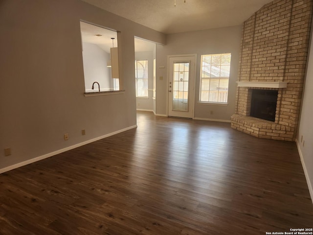 unfurnished living room featuring dark wood finished floors, a fireplace, and baseboards