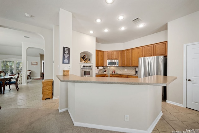 kitchen featuring light tile patterned floors, visible vents, stainless steel appliances, and arched walkways