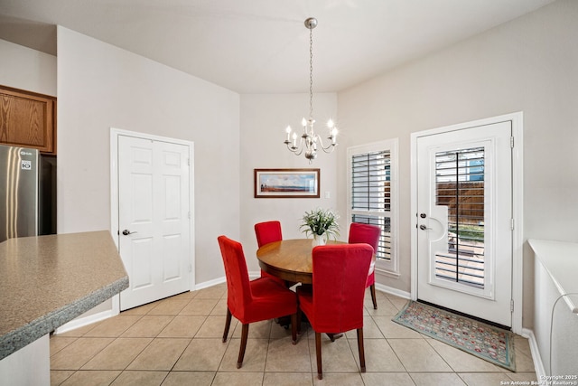 dining space featuring light tile patterned floors, a chandelier, and baseboards