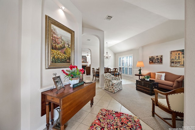 living room with light tile patterned flooring, a notable chandelier, visible vents, baseboards, and vaulted ceiling