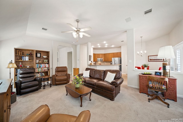 living area with light colored carpet, visible vents, arched walkways, and ceiling fan with notable chandelier