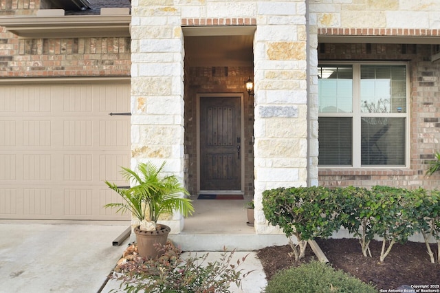 entrance to property featuring stone siding, brick siding, and an attached garage