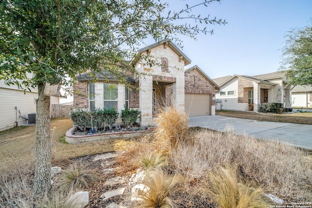 view of front of home featuring central AC unit, concrete driveway, stone siding, an attached garage, and brick siding