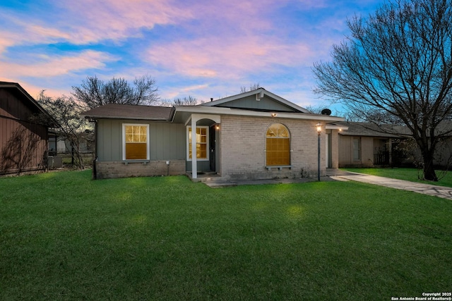 ranch-style house featuring concrete driveway, brick siding, and a yard