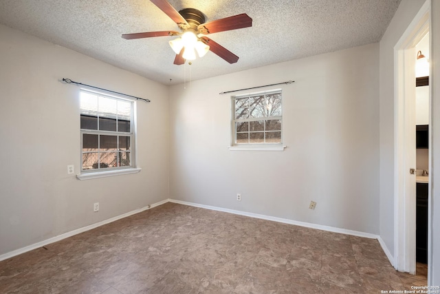 unfurnished room with a textured ceiling, a ceiling fan, and baseboards