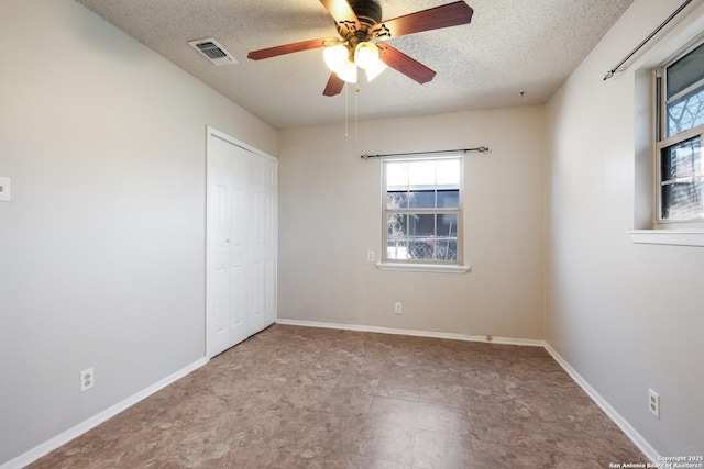 unfurnished bedroom featuring baseboards, multiple windows, visible vents, and a textured ceiling