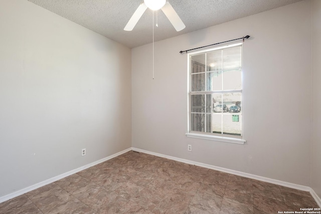 empty room with a ceiling fan, a textured ceiling, and baseboards