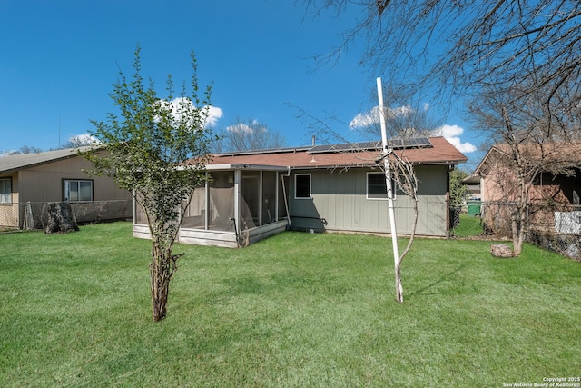 back of house featuring a yard, solar panels, a fenced backyard, and a sunroom