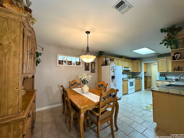 dining space with a skylight, light tile patterned floors, visible vents, a textured ceiling, and baseboards