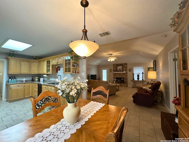 dining room featuring light tile patterned floors, a textured ceiling, a fireplace, and a ceiling fan