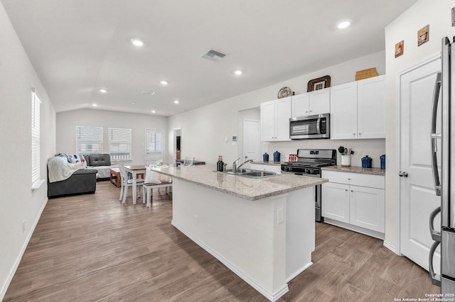 kitchen with light wood-style flooring, stainless steel appliances, a sink, white cabinetry, and open floor plan