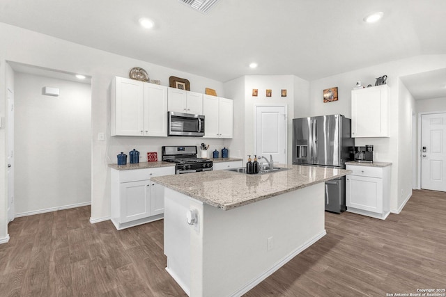 kitchen with stainless steel appliances, wood finished floors, a sink, and white cabinetry