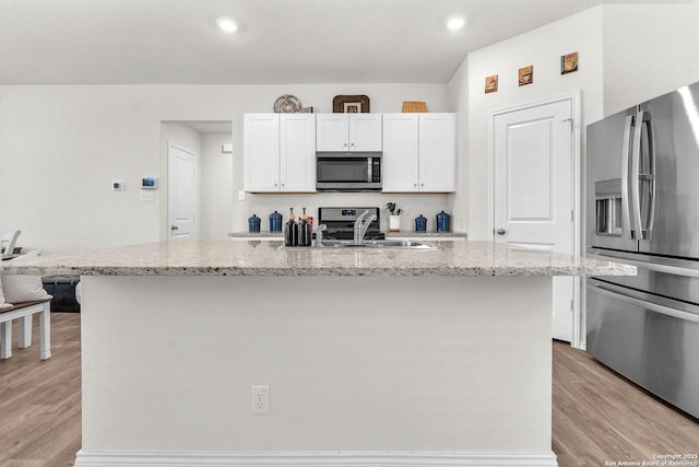 kitchen with stainless steel appliances, light wood-style floors, white cabinets, and a sink