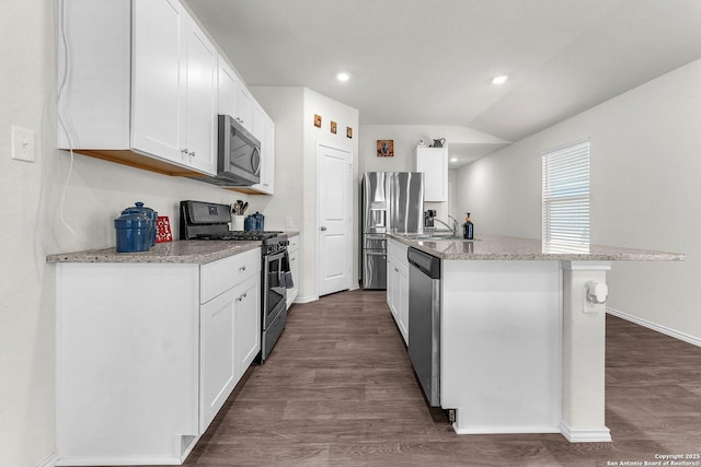 kitchen with appliances with stainless steel finishes, dark wood-style flooring, white cabinetry, and a center island with sink