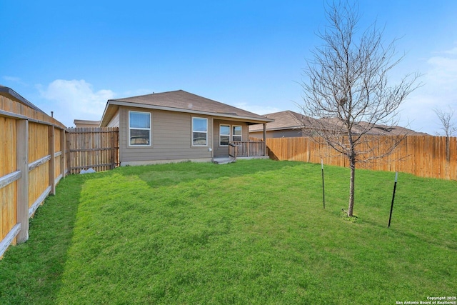 back of property with a fenced backyard and a lawn