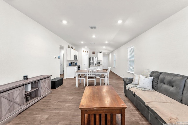 living area with wood finished floors, visible vents, and recessed lighting