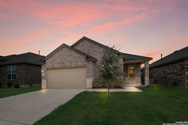 view of front of property featuring an attached garage, concrete driveway, brick siding, and a front yard