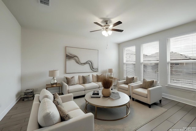 living area with a ceiling fan, visible vents, baseboards, and wood finished floors