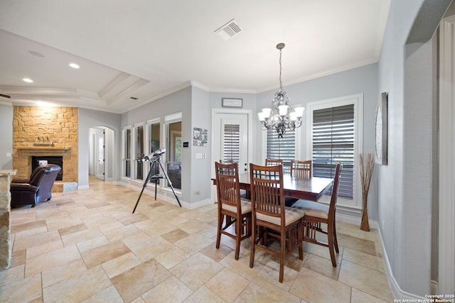 dining area with a notable chandelier, visible vents, ornamental molding, a stone fireplace, and baseboards