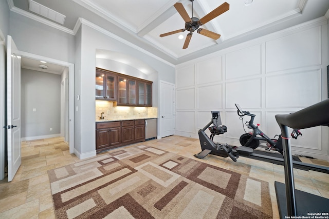 exercise room featuring crown molding, visible vents, a decorative wall, and stone tile floors