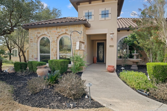 view of exterior entry with a tile roof and stucco siding