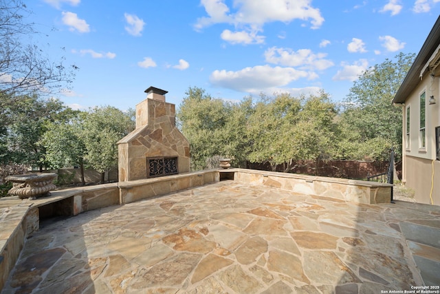 view of patio / terrace with fence and an outdoor stone fireplace