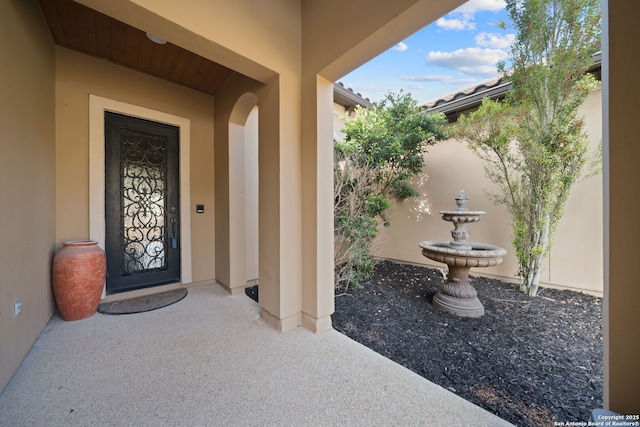 property entrance with a tiled roof and stucco siding