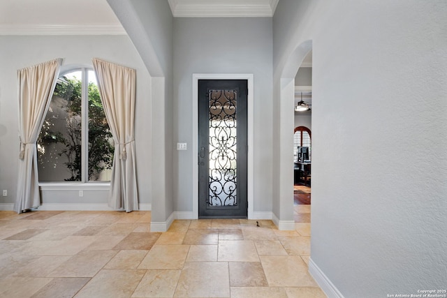 foyer entrance with baseboards, ornamental molding, and arched walkways