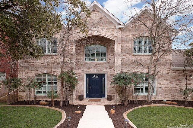 french country home featuring a front lawn and brick siding