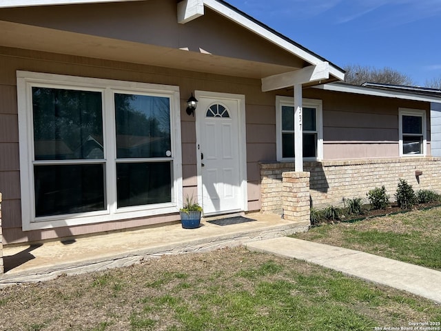 view of exterior entry featuring brick siding