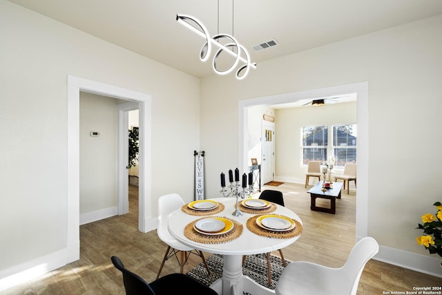 dining space featuring wood finished floors, visible vents, and baseboards