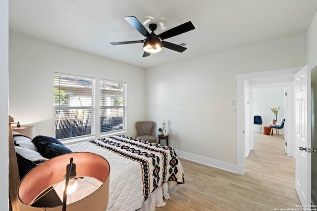 bedroom with a ceiling fan, light wood-style flooring, and baseboards