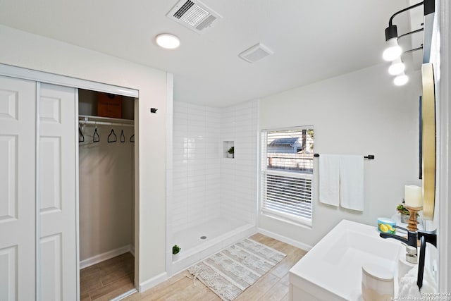 bathroom featuring a spacious closet, wood finished floors, a shower stall, and visible vents