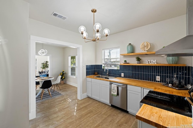 kitchen with visible vents, stainless steel dishwasher, wall chimney range hood, wooden counters, and a sink